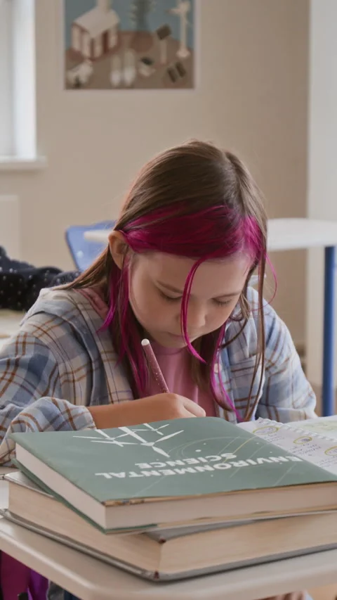 Vertical of Schoolgirl Writing Notes in Notebook during Lesson in Classroom Stock Footage 345226154