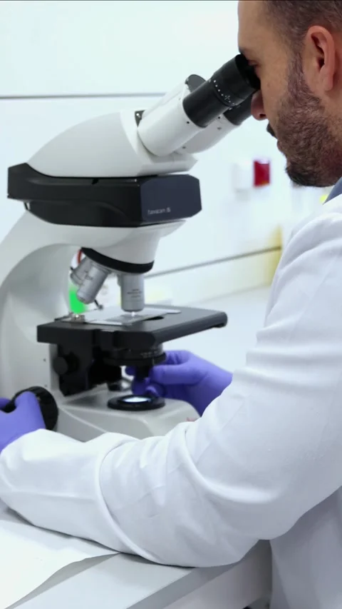 Vertical Scientist analyzing sample with microscope in laboratory Stock Footage 296886272