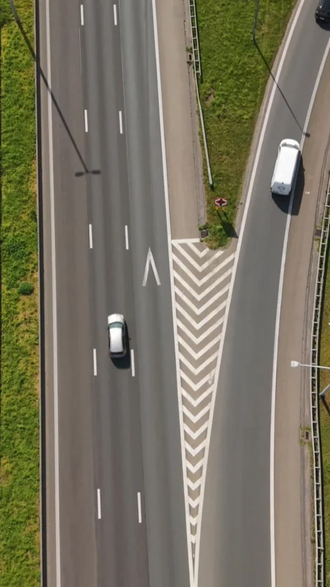 Vertical screen. Aerial perspective captures two vehicles traveling on curved Stock Footage 345861727