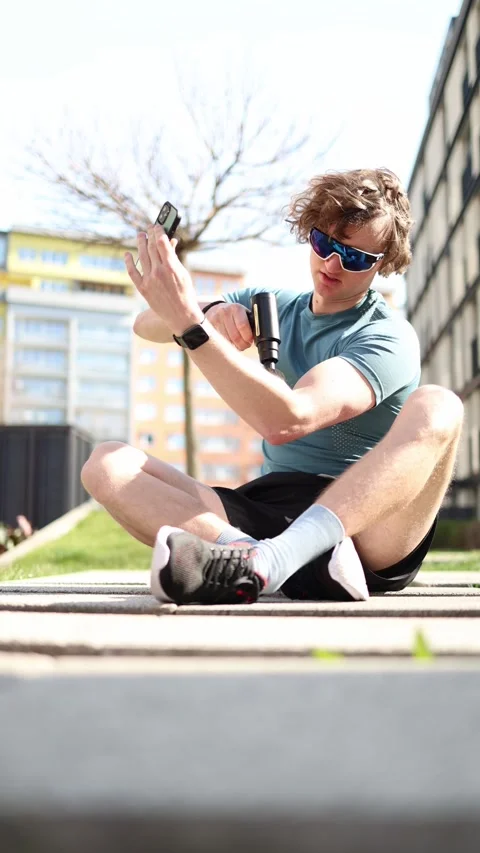 Vertical screen. After a workout, a young man gives himself a massage with a mas Stock Footage 305999114