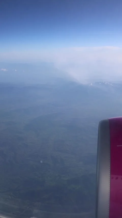 Vertical screen airplane wing view over misty mountains soft morning light hazy  Stock Footage 310471026