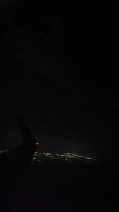 Vertical screen airplane wingtip glows above sparkling city lights in deep night Stock Footage 310467130