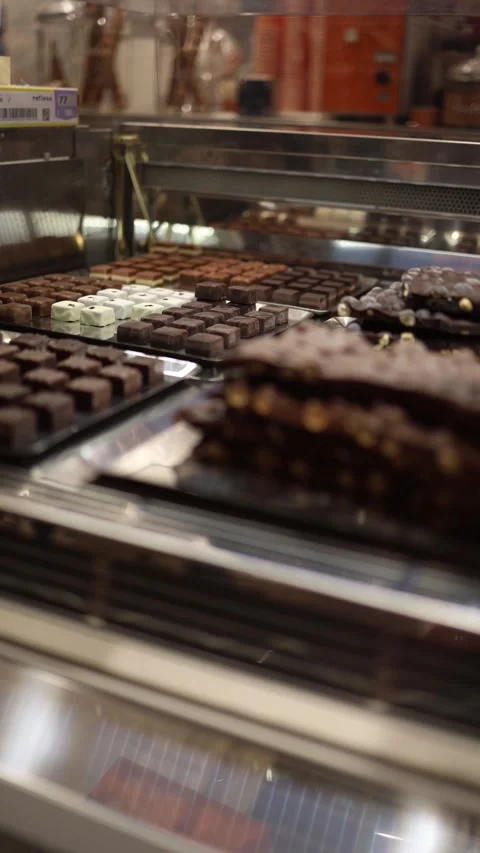 Vertical screen assorted handcrafted chocolates in glass display sparkle under w Stock Footage 310470034