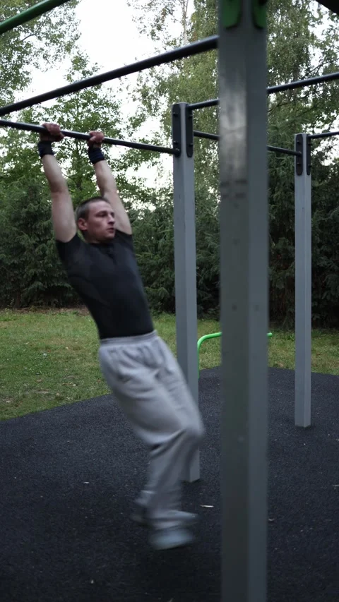 Vertical screen athletic boy performs front lever on outdoor bar holding body st Stock Footage 316700348