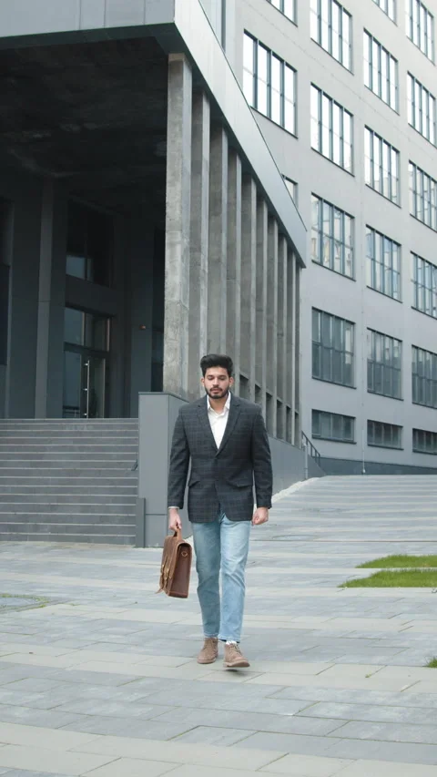 Vertical Screen: Attractive businessman walking outside near big office building Stock Footage 272665583