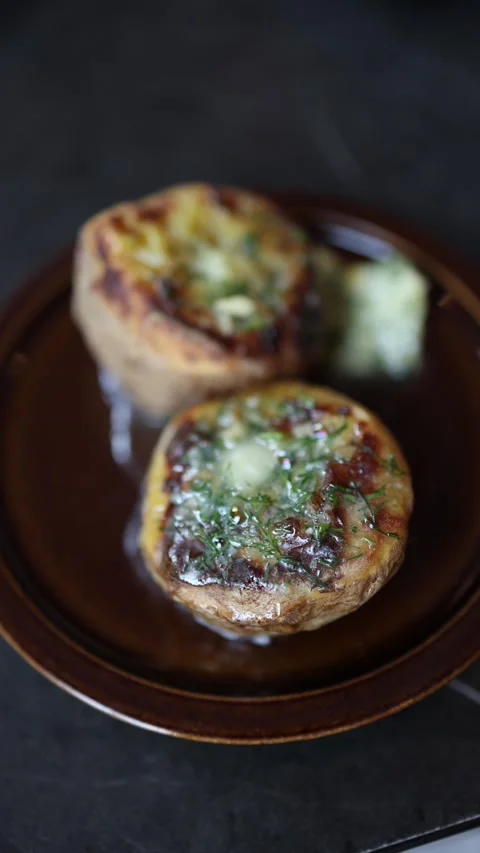 Vertical screen Baked potatoes with melted butter and fresh herbs served on a ru Stock Footage 312697098