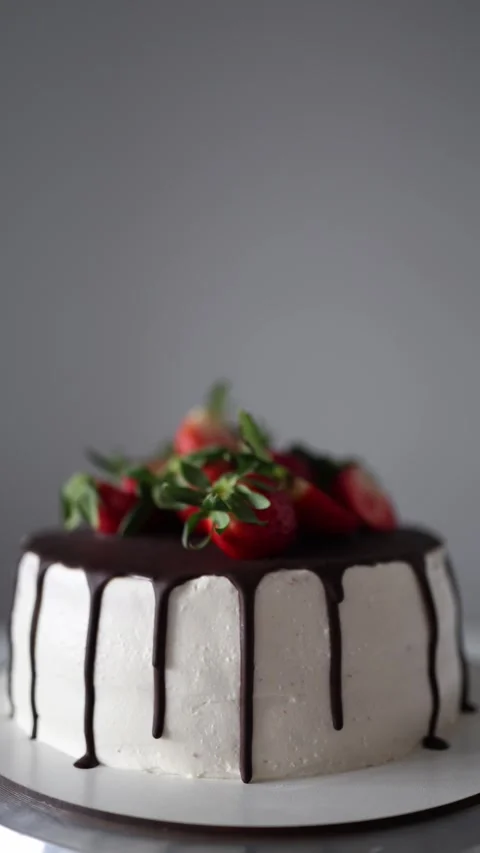 Vertical screen: A beautiful cake topped with fresh strawberries and drizzled wi Stock Footage 302794257