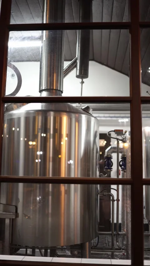 Vertical screen: Behind the window, a polished brewing tank glows under bright w Stock Footage 307623675