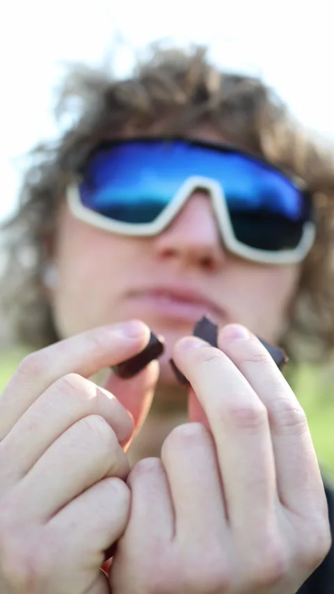 Vertical screen bold bite under bright sun sporty shades chocolate in hand wild  Stock Footage 305999177