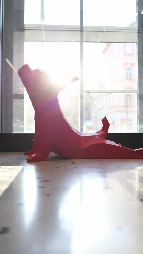 Vertical screen: A bold red geometric dog sculpture sits by the window, bathed i Stock Footage 304459518