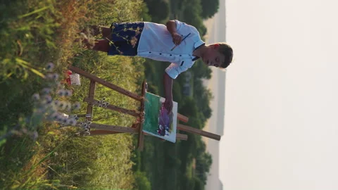 Vertical Screen: Boy painting on canvas in nature Stock Footage 244044837