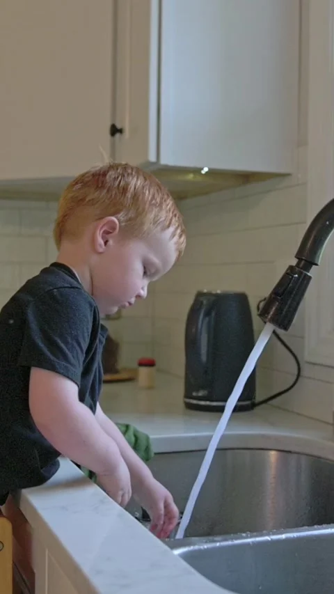 Vertical screen boy with red hair doing household chores carefully, blonde boy Stock Footage 323778147