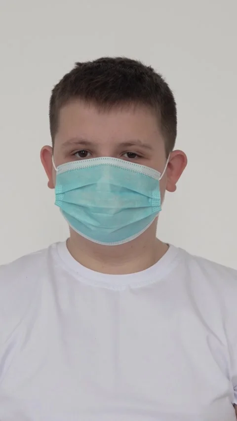 Vertical screen: A boy wears a mask during the coronavirus pandemic. Close-up in Stock Footage 263237844