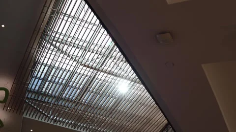 Vertical screen bright sunlight streams through modern glass ceiling with parall Stock Footage 317506972