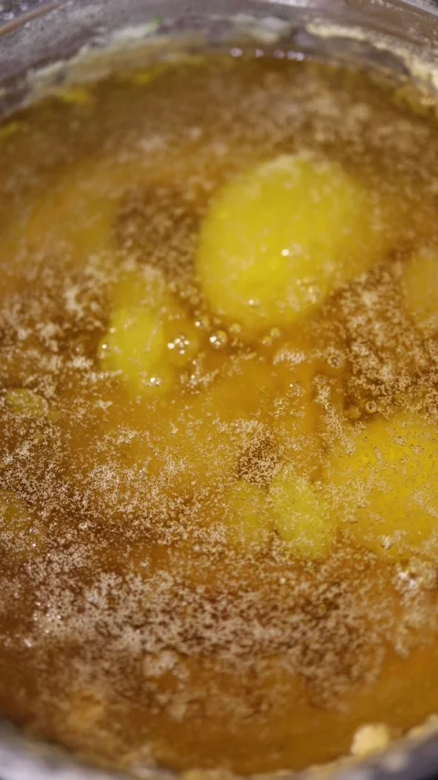 Vertical screen bubbling golden butter boiling in pot during ghee preparation sh Stock Footage 319242634