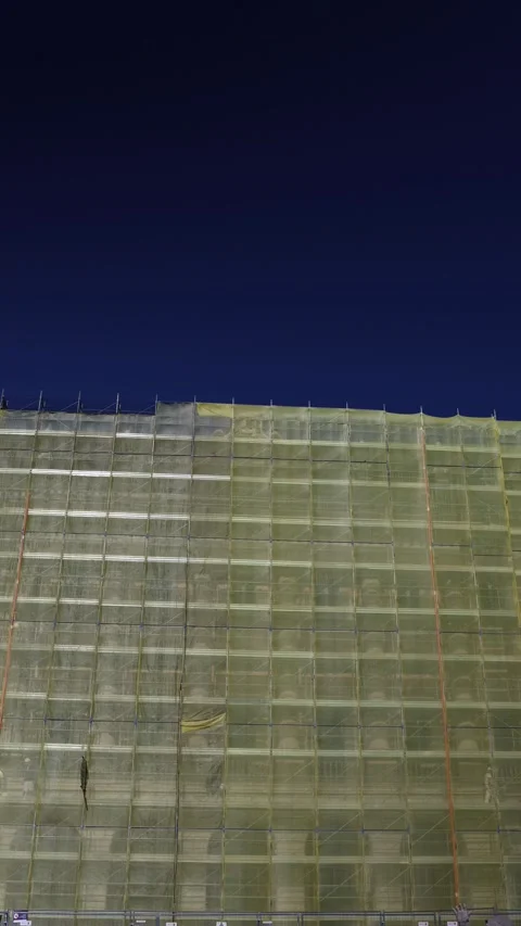 Vertical screen building under renovation covered in yellow mesh scaffolding fad Stock Footage 310468763