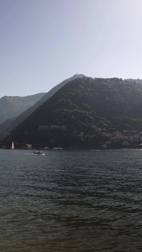 Vertical screen calm lake view with seaplane gliding across water lush green mou Stock Footage 310469751