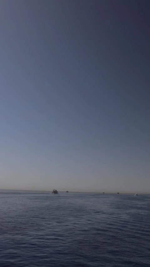 Vertical screen calm sea horizon stretches under soft morning light boats glide  Stock Footage 310517119