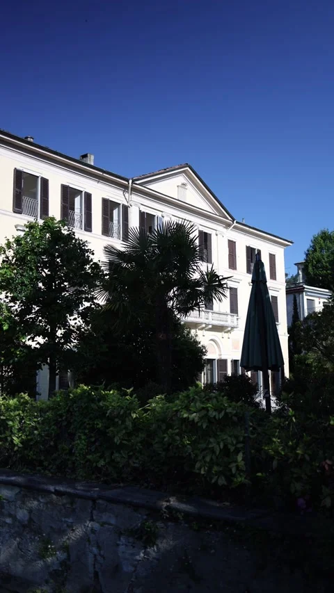 Vertical screen charming villa facade glows under deep blue sky surrounded by ri Stock Footage 310468164