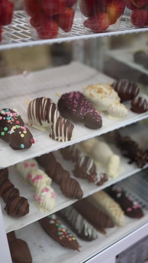 Vertical screen: Chocolate-covered strawberries with various toppings like sprin Stock Footage 303286012