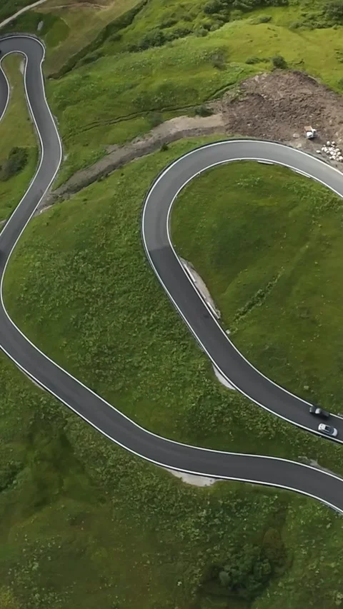 Vertical screen Cinematic aerial sweeping mountain bend with smooth asphalt Vidéo 325059637