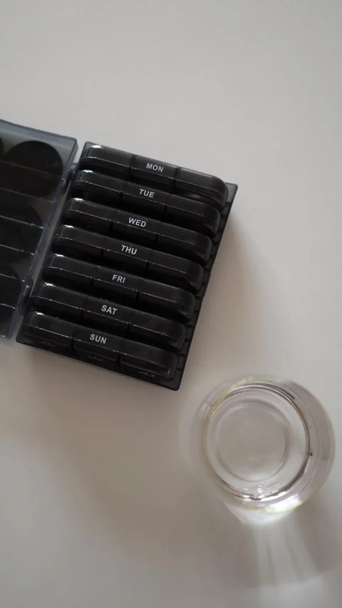 Vertical screen: On a clean, bright surface, pill organizers for the week and a  Stock Footage 301240119