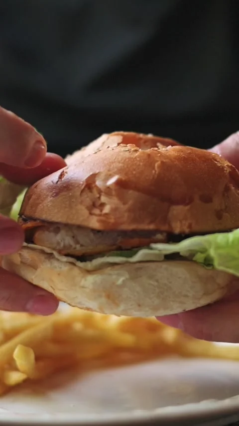 Vertical screen close-up fried chicken burger with crispy lettuce inside toasted 動画素材 306715574