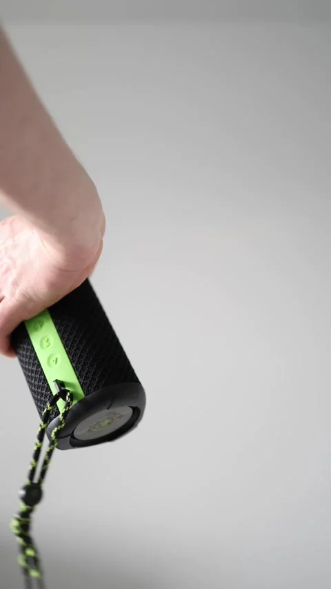 Vertical screen: Close-up of a hand holding a portable wireless black speaker on Stock Footage 303908391
