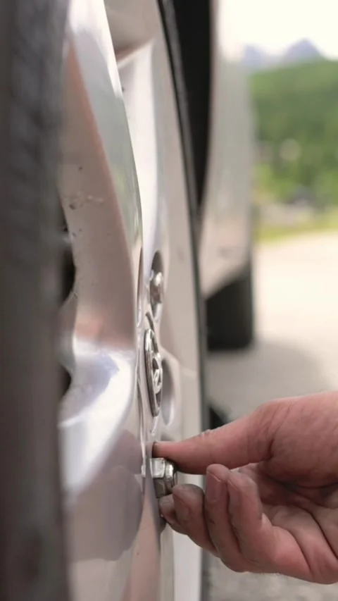 Vertical screen close-up of hand tightening bolts on car wheel during emergency Stock Footage 318355389