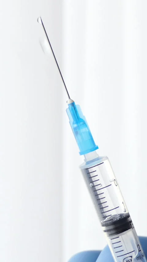 Vertical Screen: Close-up of an injection liquid in a syringe on a white Stock Footage 232264878