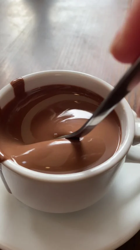 Vertical screen: Close-up melted liquid chocolate flows, metal pastry spoon Stock Footage 263129781