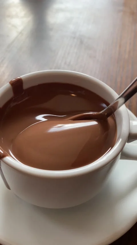Vertical screen: Close-up melted liquid chocolate flows, metal pastry spoon Stock Footage 263439102