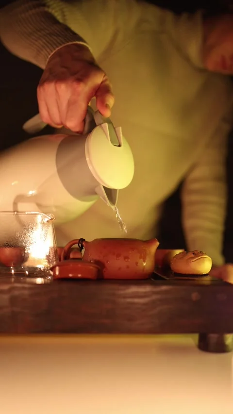 Vertical screen: A close-up of water being poured from a thermos into a traditio Video stock 299379603