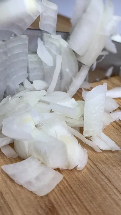 Vertical screen: Close-up of a woman's hand cutting a fresh white onion on a Stock Footage 240873594