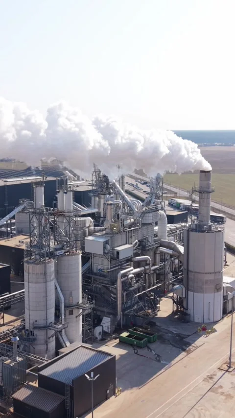 Vertical screen Coastal Industrial Facility Releasing Dense Smoke, Towering Stock Footage 333638844