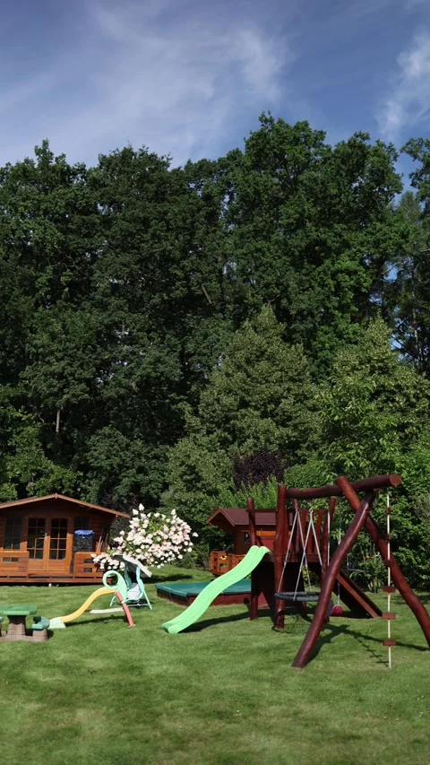 Vertical screen Colorful playground with slides and swings stands on bright gree Stock Footage 313843600