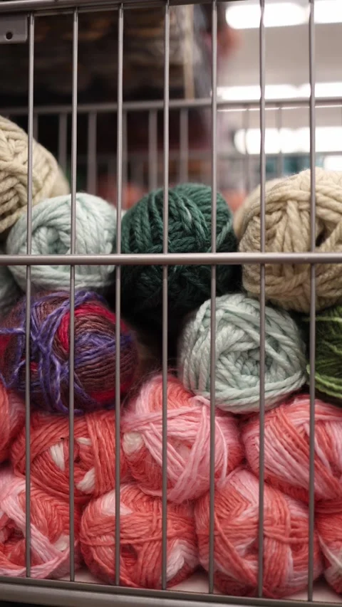 Vertical screen colorful yarn balls stacked behind a metal grid basket Stock Footage 330014805
