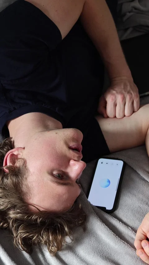 Vertical screen communication with artificial intelligence young man lies on bed Stock Footage 314979555