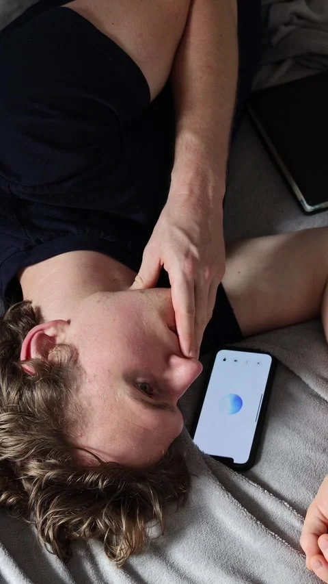 Vertical screen communication with artificial intelligence young man lies on bed Stock Footage 314979560