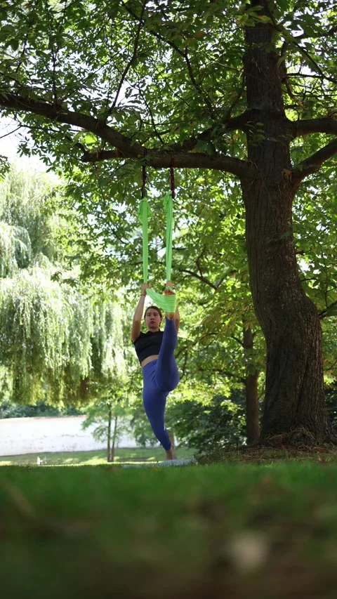Vertical screen confident and graceful woman stands in aerial yoga pose raising  Stock Footage 313378551