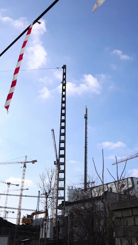 Vertical screen: A construction site with towering cranes and a tall metal struc Stock Footage 303850551