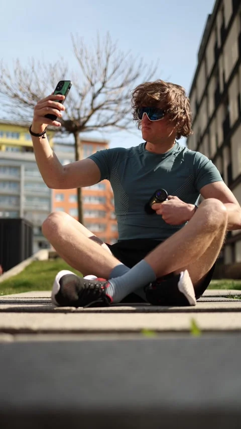 Vertical screen. A content creator records himself using a massage gun after a w Vídeo Stock 305999133