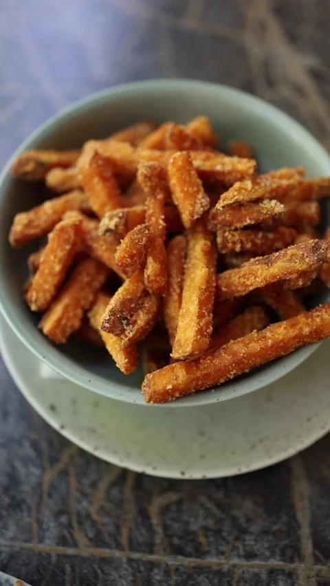 Vertical screen crispy sweet potato fries stacked in rustic ceramic bowl golden  Video stock 309327345