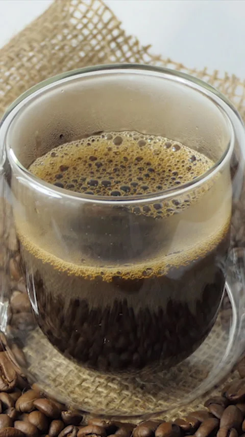 Vertical Screen: Cup of coffee with fresh roasted coffee beans background. A Stock Footage 229974894