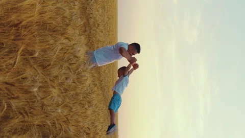 Vertical Screen: Dad spinning around little son in field in slow motion Stock Footage 167499833