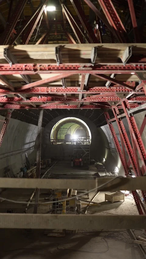 Vertical screen deep tunnel construction site framed by red steel scaffolding an Stock Footage 309653045