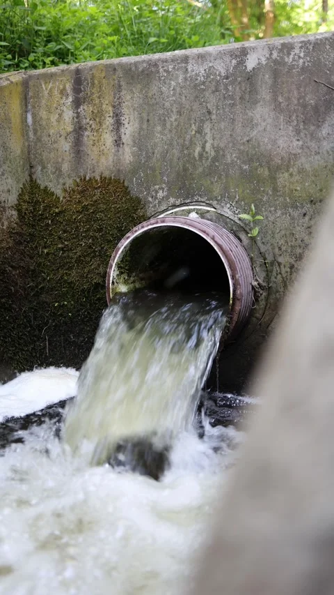 Vertical screen dirty foamy water rushes from rusty drainage pipe splashing agai Stock Footage 309329555