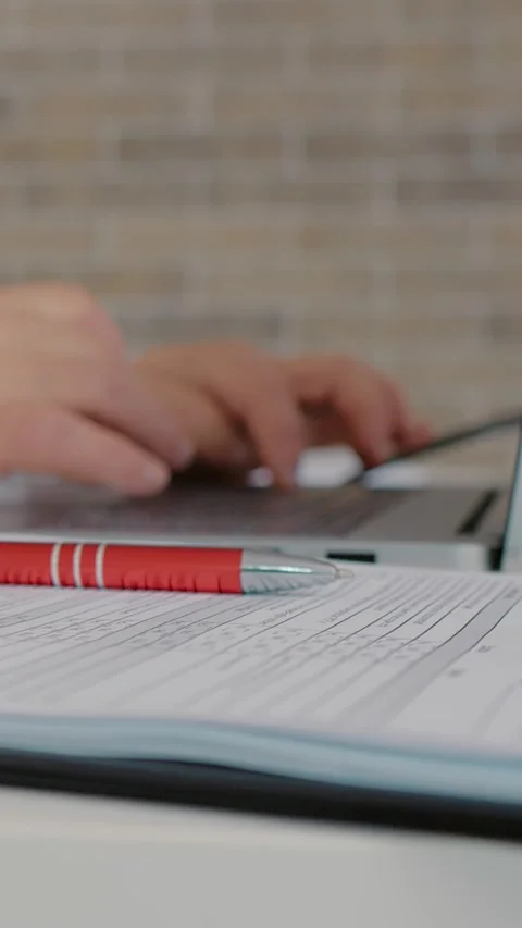 Vertical Screen Doctor hands typing on laptop having checklists on her right Stock Footage 299991345