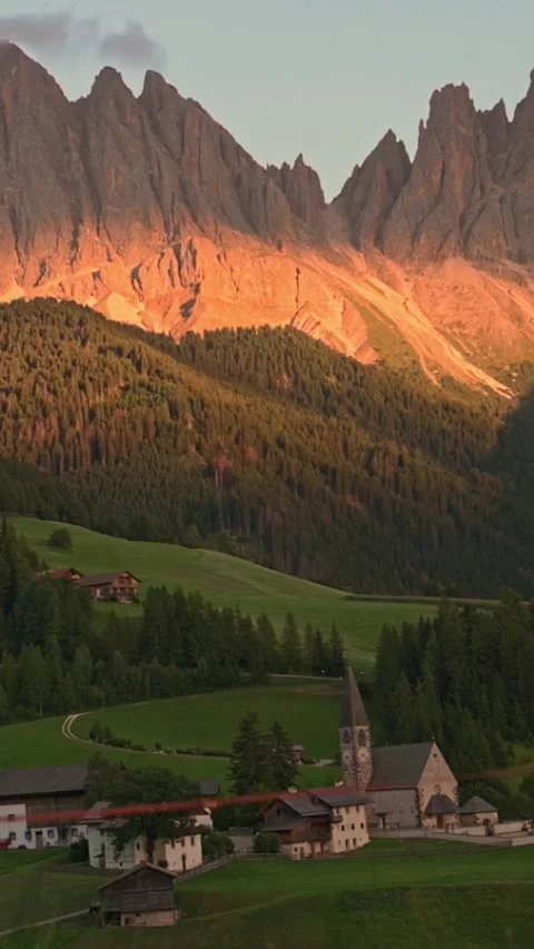 Vertical screen dolomites glowing peaks in sunset light above alpine village Stockbeeldmateriaal 318724774
