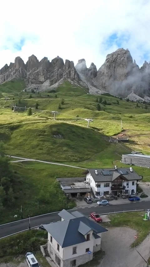 Vertical screen Dolomites ridge road with cottages, lush hillside under jagged Vídeo Stock 323242756